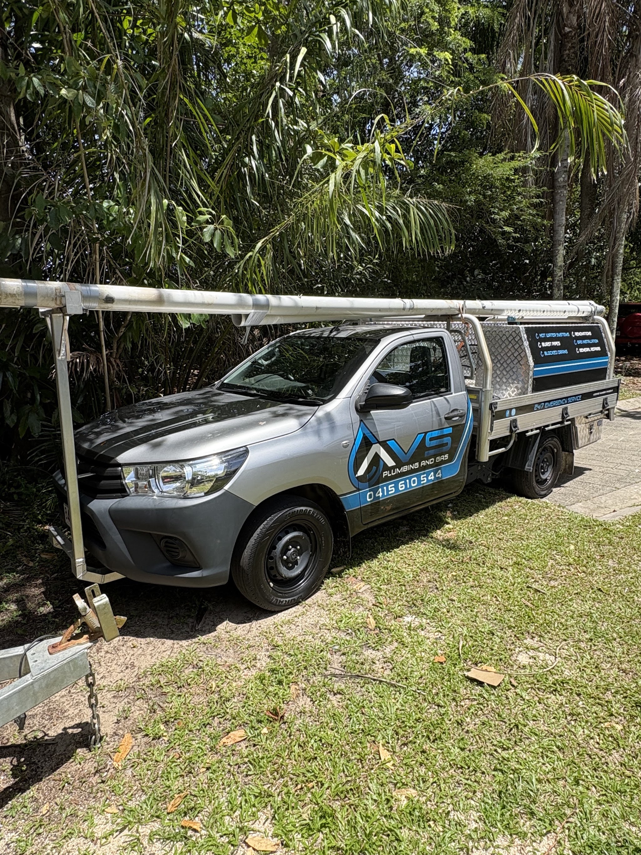 The AVS Plumbing and Gas Hilux with a roof rack pipe carrier, signwritten with hot water systems, burst pipes, blocked drains, renovations, gas installation and general repairs