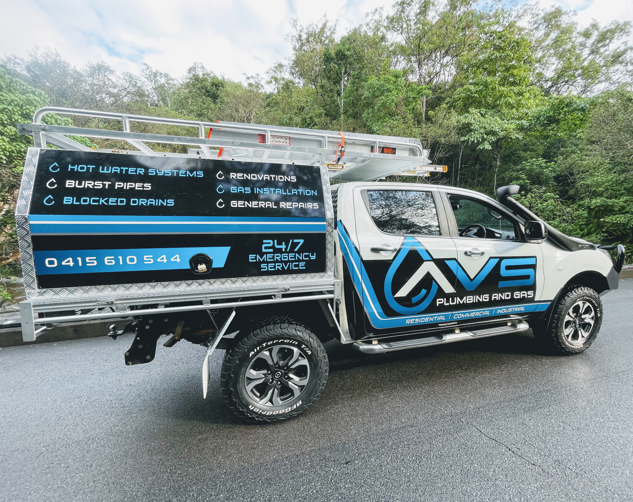 The AVS Plumbing and Gas ute, signwritten with its service list and phone number, on a road north of Cairns